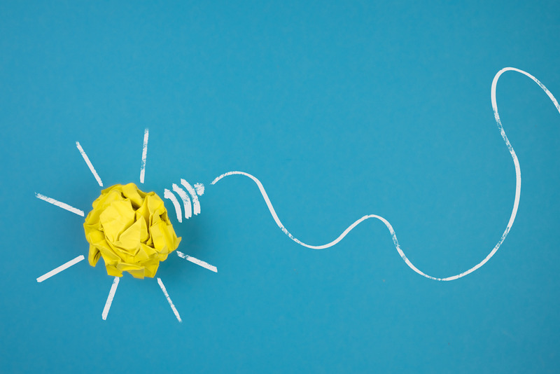 light bulb made of crumpled-up yellow paper on blue background, idea and innovation concept
