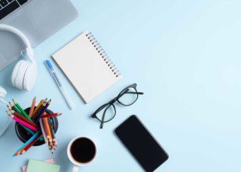 A notebook, pencils and glasses on a blue table