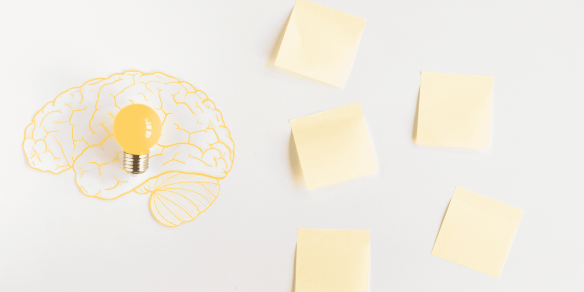 5 Post-it jaunes sur une table avec à gauche un dessin d'un cerveau jaune avec une ampoule au centre jaune aussi