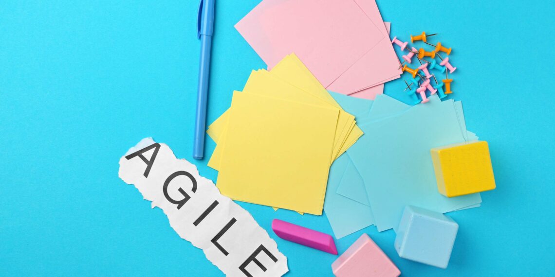 Plusieurs post-it sur un fond bleu clair avec un papier avec écrit 'agile" dessus