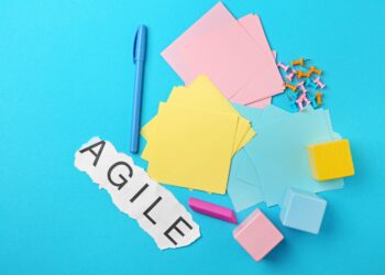 Plusieurs post-it sur un fond bleu clair avec un papier avec écrit 'agile" dessus