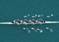 A team of 4 rowers rowing together on a blue lagoon