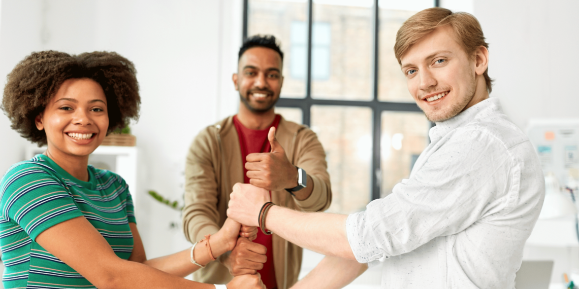 Trois membres de l'équipe participent activement à un jeu collectif. Ils sont disposés en cercle dans un espace ouvert et dégagé, souriants et concentrés.