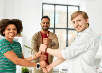 Trois membres de l'équipe participent activement à un jeu collectif. Ils sont disposés en cercle dans un espace ouvert et dégagé, souriants et concentrés.
