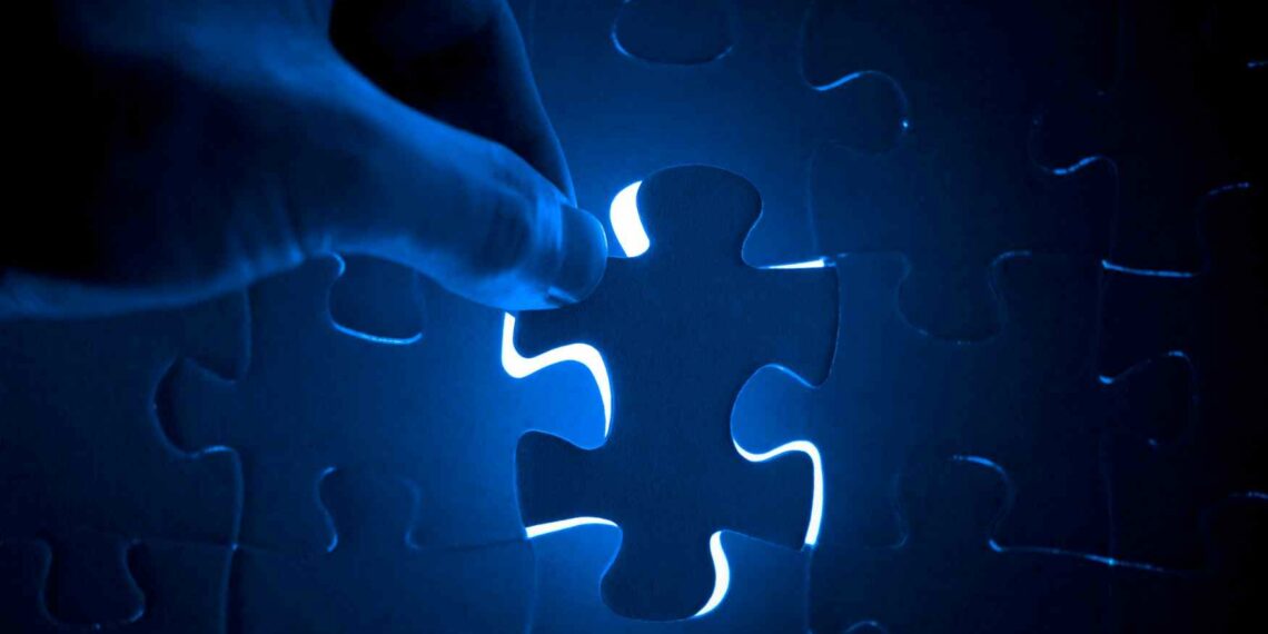 Main qui tient une pièce de puzzle bleu