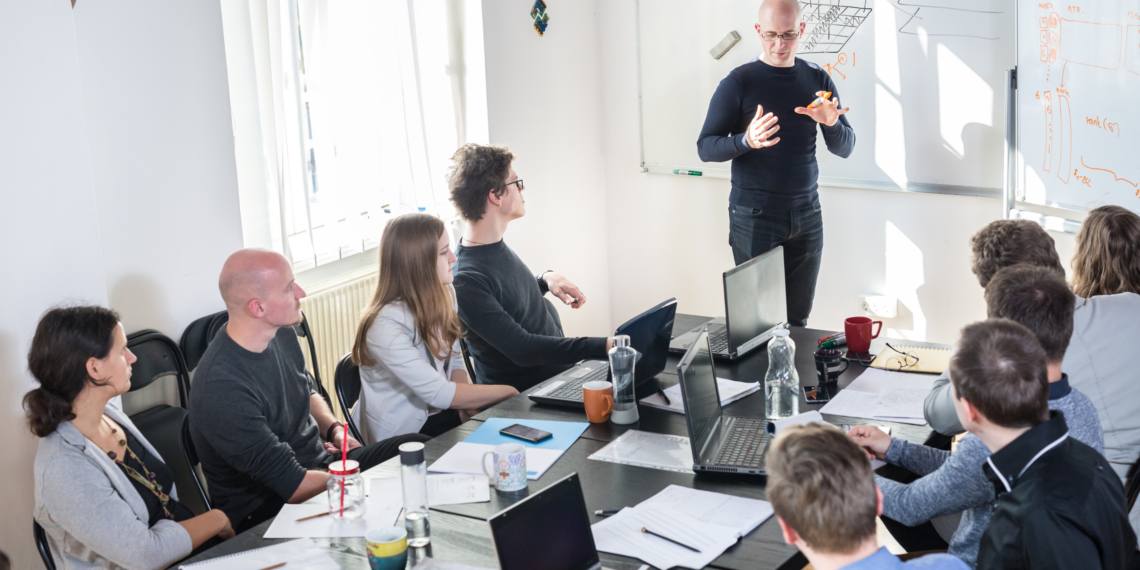 Personnes attablées à un meeting, écoutant leur manager. Intégrant l'IA en entreprise